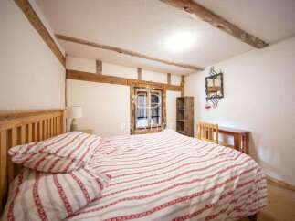 Discover the charm of this cozy bedroom, featuring exposed wooden beams and a rustic aesthetic.