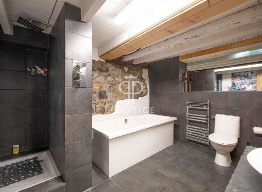 Discover the charm of this unique bathroom, featuring a striking stone wall and modern fixtures.