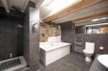 Discover the charm of this unique bathroom, featuring a striking stone wall and modern fixtures.