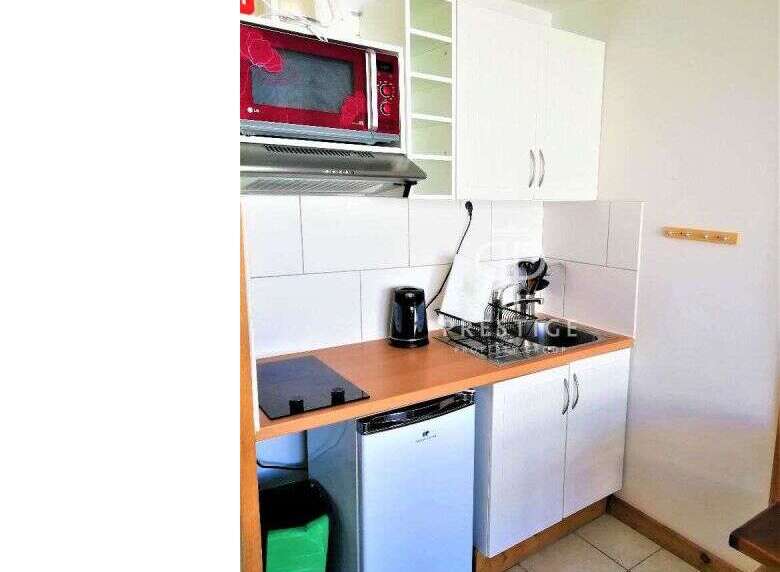 Cozy studio apartment with a compact kitchen, perfect for efficient living.