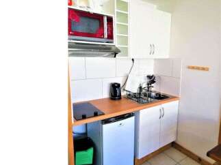 Cozy studio apartment with a compact kitchen, perfect for efficient living.