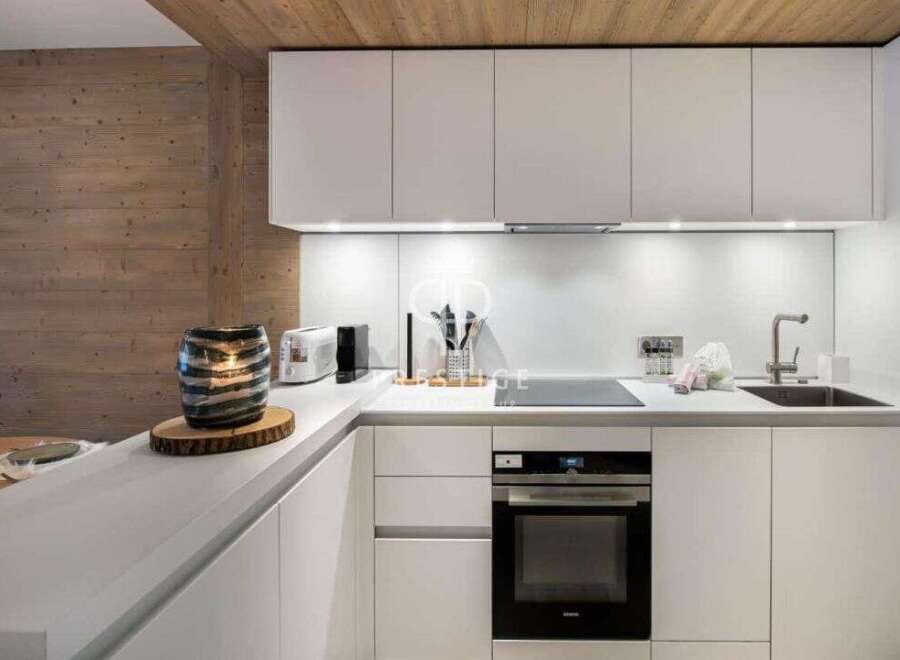 This modern kitchen boasts sleek white cabinetry and countertops, creating a bright and airy atmosphere.