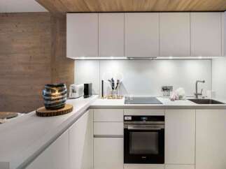 This modern kitchen boasts sleek white cabinetry and countertops, creating a bright and airy atmosphere.