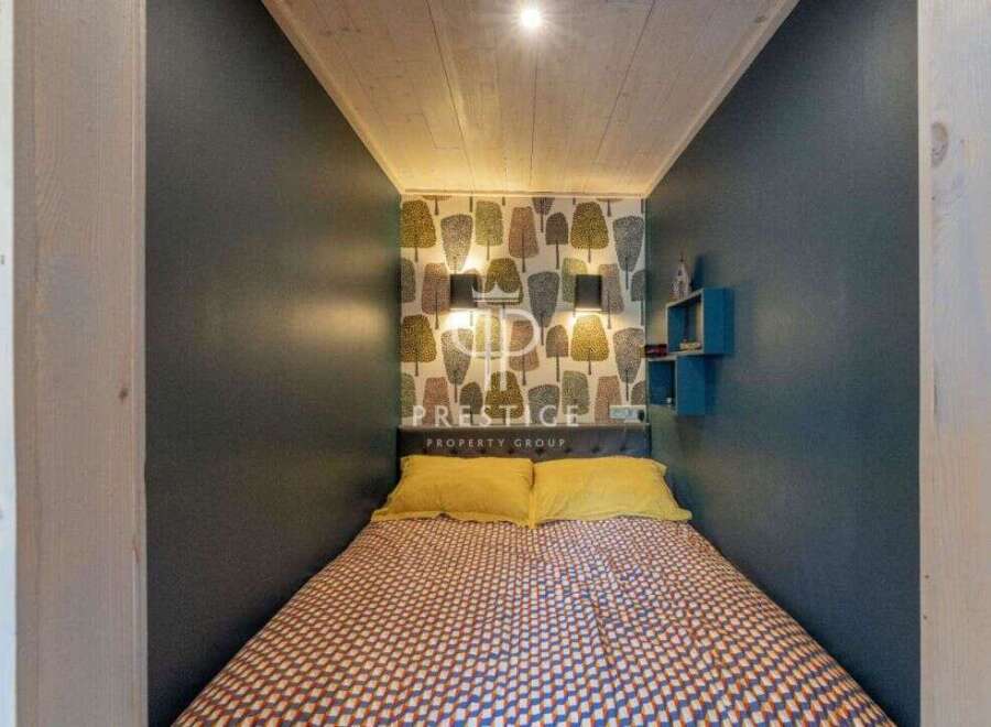 Discover a cozy bedroom retreat! This space features a unique tree-patterned wallpaper, complemented by stylish wall lamps and a comfortable bed.