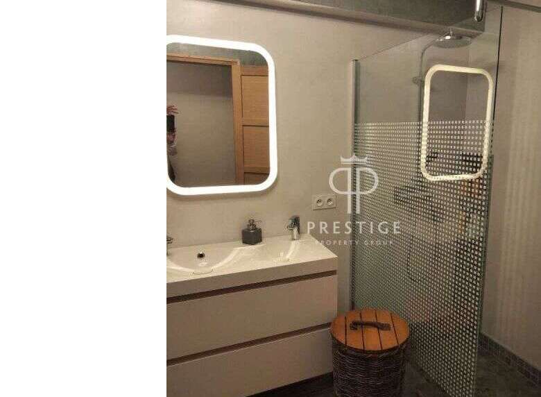 Modern bathroom design featuring a sleek vanity with a built-in sink and a stylish illuminated mirror.