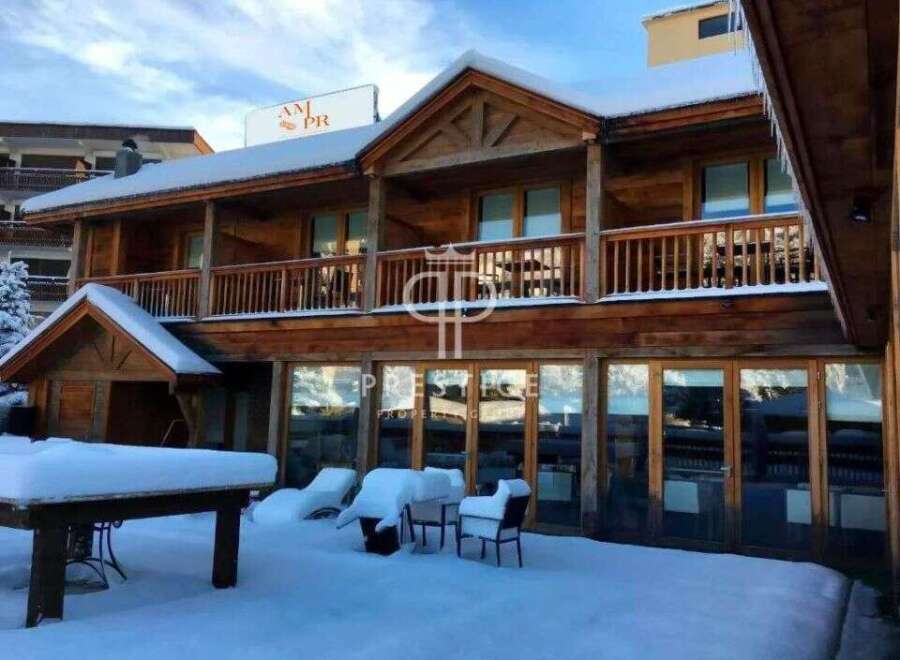 Discover a stunning wooden chalet nestled in a snowy landscape, perfect for a winter getaway.