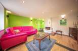 Discover this stunning property featuring a vibrant living room with a bold pink sofa and a striking green accent wall.