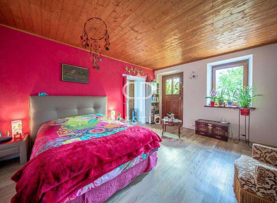 Charming bedroom with a vibrant pink accent wall and a cozy wooden ceiling.