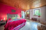 Charming bedroom with a vibrant pink accent wall and a cozy wooden ceiling.