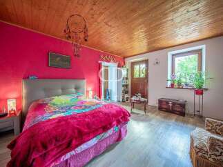 Charming bedroom with a vibrant pink accent wall and a cozy wooden ceiling.