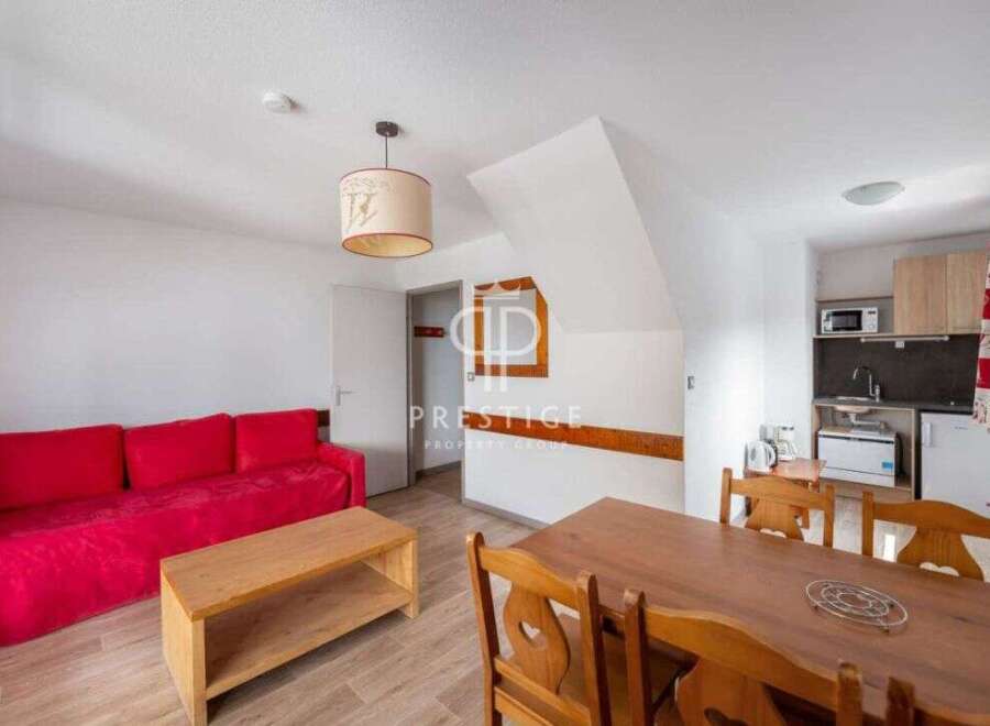 Discover this charming property featuring a cozy red sofa and a stylish wooden coffee table, perfect for relaxation.