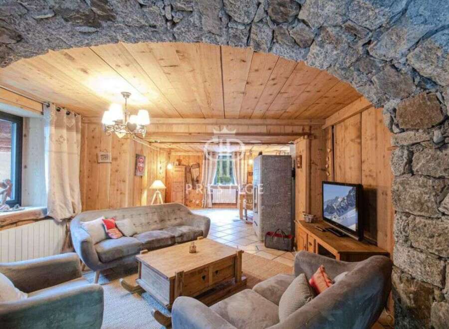 Discover the charm of this cozy living space, featuring a stunning stone archway and warm wooden accents.