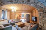 Discover the charm of this cozy living space, featuring a stunning stone archway and warm wooden accents.