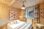 Cozy cabin bedroom with rustic wooden walls and ceiling.