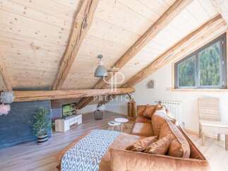 Discover the charm of this stunning property, featuring a cozy living space with exposed wooden beams and a unique sloped ceiling.