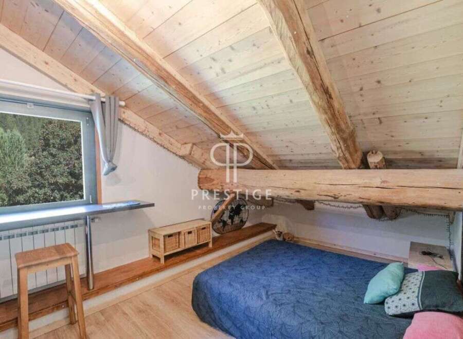 Discover the charm of this unique property, featuring a cozy bedroom with a stunning wooden ceiling and exposed beams.
