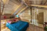 Discover the charm of this cozy bedroom, featuring a rustic wooden interior and a comfortable bed.