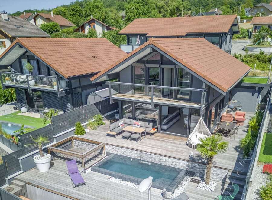 Luxury modern house with stunning outdoor features including a deck, infinity pool, and landscaping.