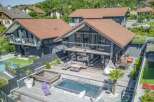 Luxury modern house with stunning outdoor features including a deck, infinity pool, and landscaping.