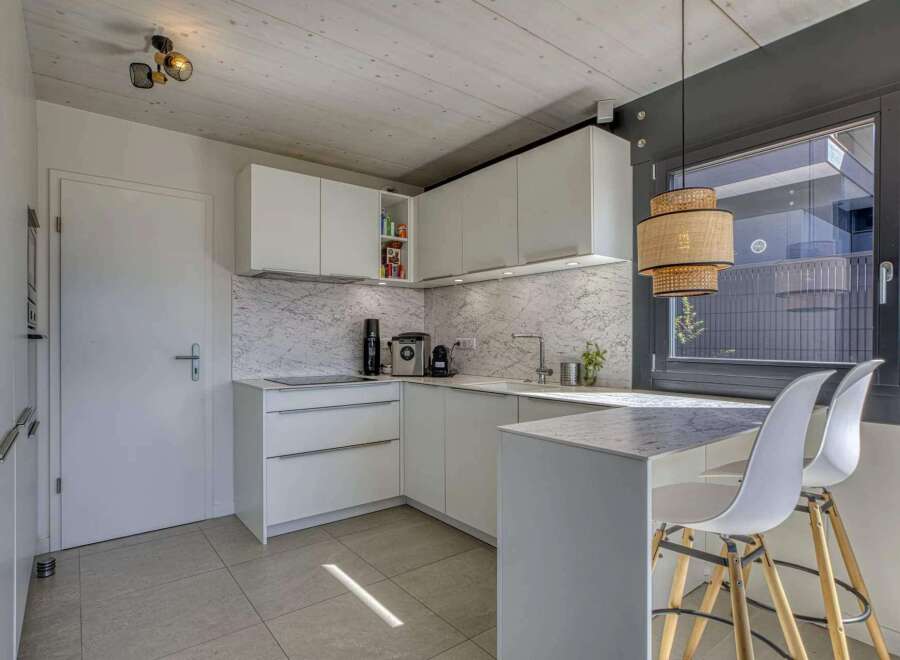 Modern kitchen with white cabinets and marble countertops.