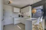 Modern kitchen with white cabinets and marble countertops.