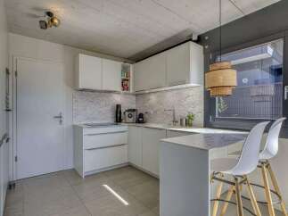 Modern kitchen with white cabinets and marble countertops.