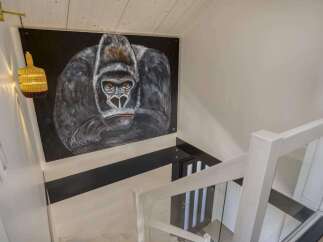 Stunning modern home featuring a dramatic gorilla painting as a statement piece above the staircase.