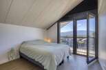 Wake up to breathtaking mountain views from this bedroom with floor-to-ceiling windows and a private balcony.