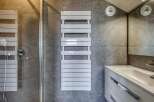 Modern bathroom with sleek gray tile, a frameless glass shower enclosure, and a contemporary white heated towel rack.