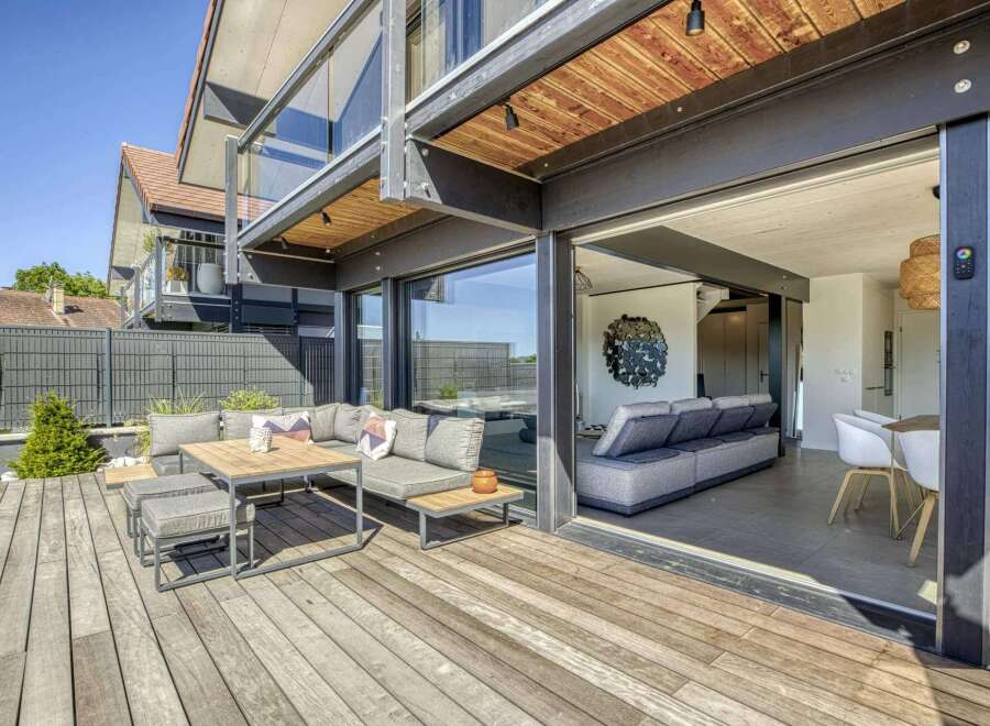 This stunning property boasts a spacious deck perfect for outdoor entertaining, complete with comfortable seating and a modern dining set.