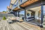 This stunning property boasts a spacious deck perfect for outdoor entertaining, complete with comfortable seating and a modern dining set.