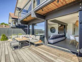 This stunning property boasts a spacious deck perfect for outdoor entertaining, complete with comfortable seating and a modern dining set.