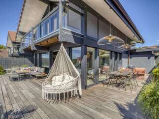 Stunning modern home with spacious deck and outdoor seating area, perfect for entertaining.