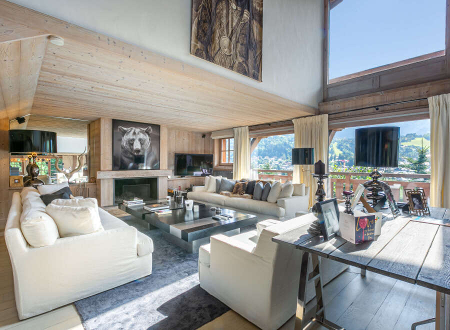 Luxurious chalet living room with floor-to-ceiling windows offering breathtaking mountain views.