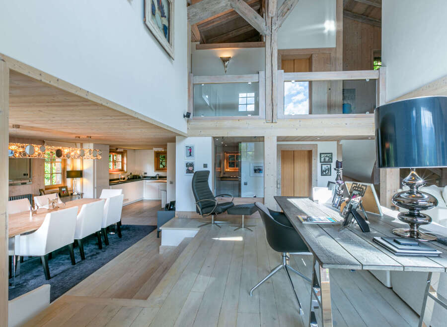 This stunning chalet boasts a spacious open-plan living area with high ceilings and exposed wooden beams, creating a warm and inviting atmosphere.
