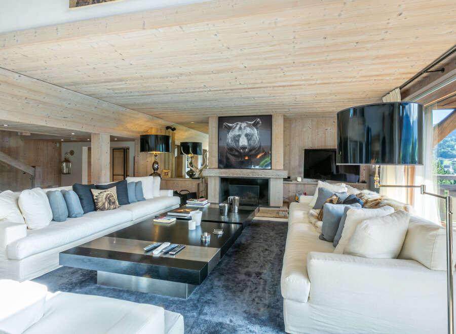 Luxurious chalet living room with floor-to-ceiling windows offering breathtaking mountain views.