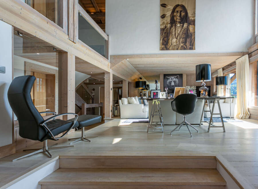 This stunning chalet boasts a spacious open-plan living area with exposed wooden beams and large windows offering breathtaking views.