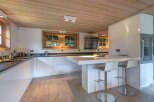 Modern kitchen with white cabinets and wooden ceiling.