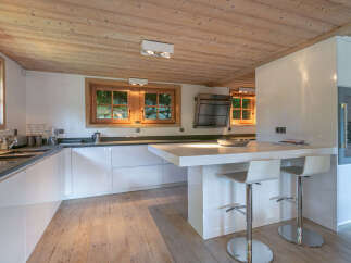 Modern kitchen with white cabinets and wooden ceiling.