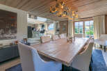 This stunning chalet boasts a spacious dining area with a rustic wooden table, complemented by elegant white chairs and a unique chandelier.
