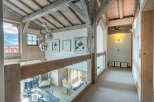 This stunning chalet boasts a breathtaking view and unique architectural details, including exposed wooden beams and a glass-walled upper hallway.