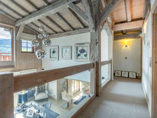 This stunning chalet boasts a breathtaking view and unique architectural details, including exposed wooden beams and a glass-walled upper hallway.