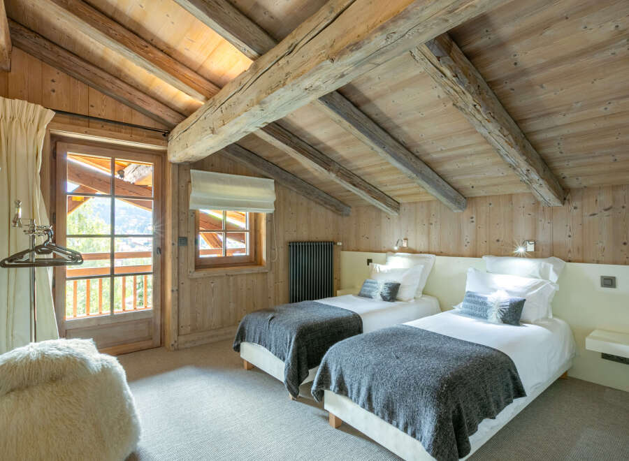 Cozy chalet bedroom with exposed wooden beams and a view.