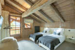 Cozy chalet bedroom with exposed wooden beams and a view.