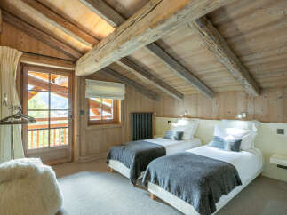 Cozy chalet bedroom with exposed wooden beams and a view.