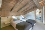 Cozy chalet bedroom with twin beds, exposed wooden beams, and a neutral color palette.