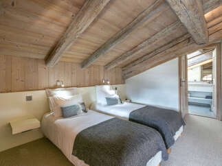 Cozy chalet bedroom with twin beds, exposed wooden beams, and a neutral color palette.