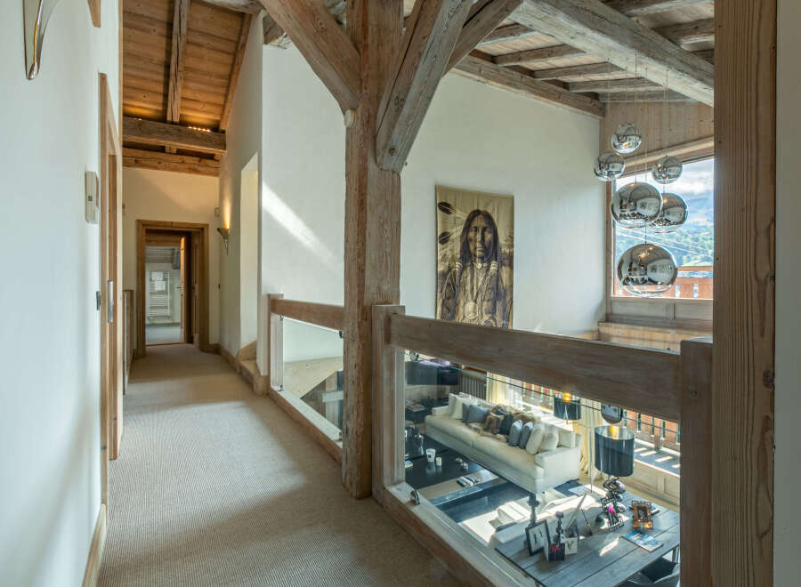 This stunning chalet boasts a spacious hallway with high ceilings and exposed wooden beams, creating a warm and inviting atmosphere.