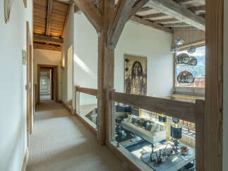 This stunning chalet boasts a spacious hallway with high ceilings and exposed wooden beams, creating a warm and inviting atmosphere.