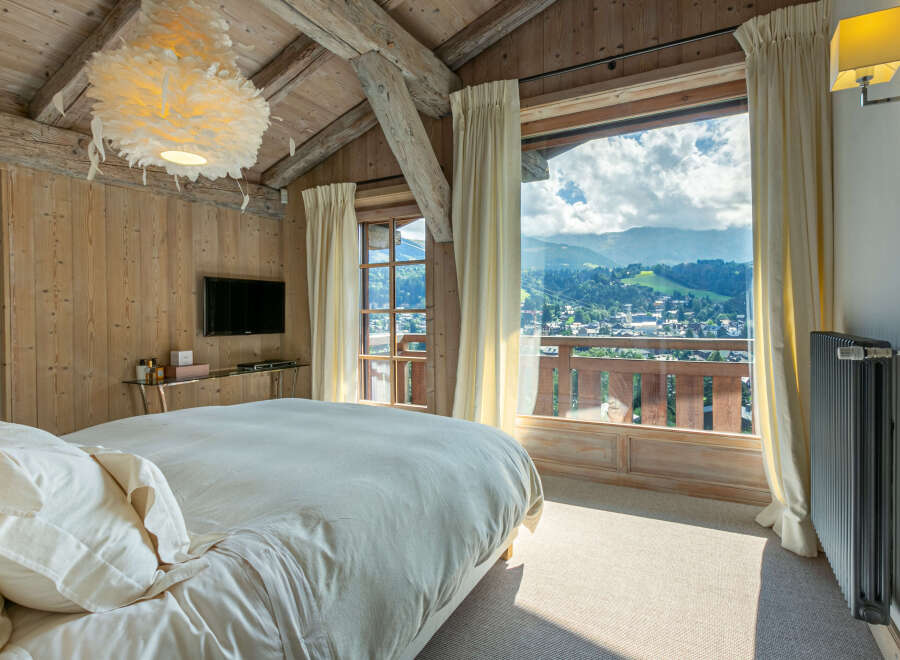 Wake up to breathtaking mountain views from this luxurious chalet bedroom.